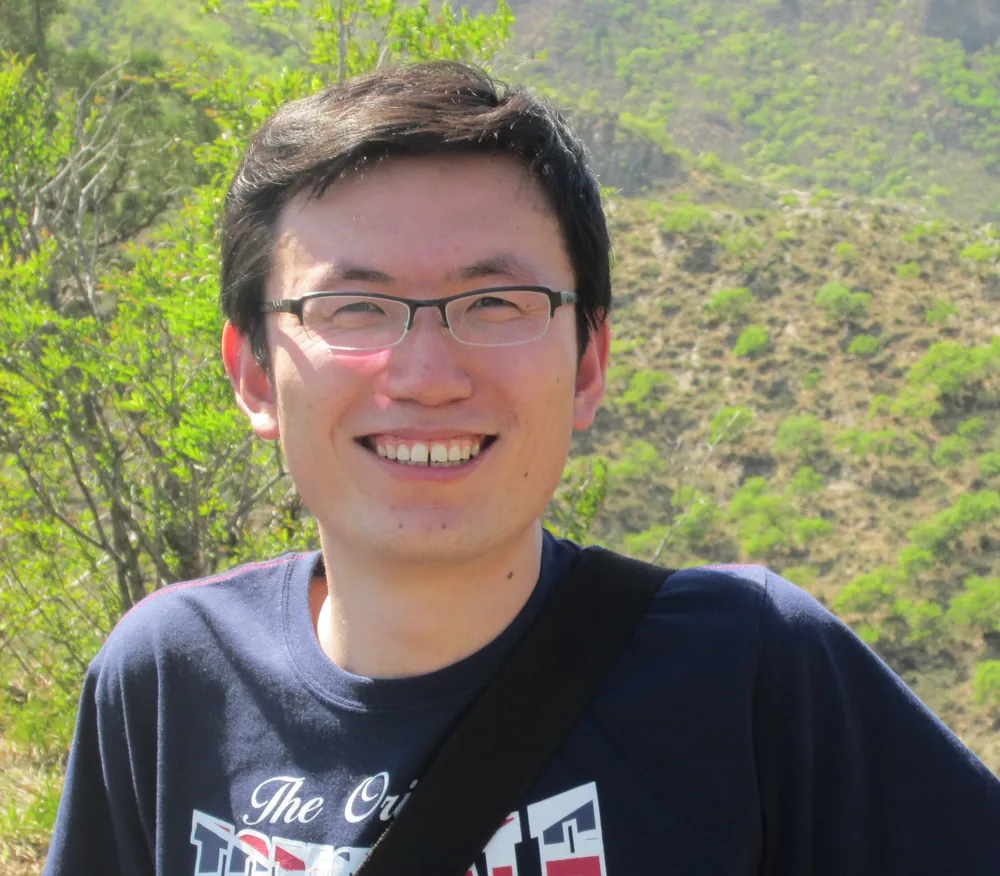 Portrait of Guoxin Cui outdoors on a green hillside